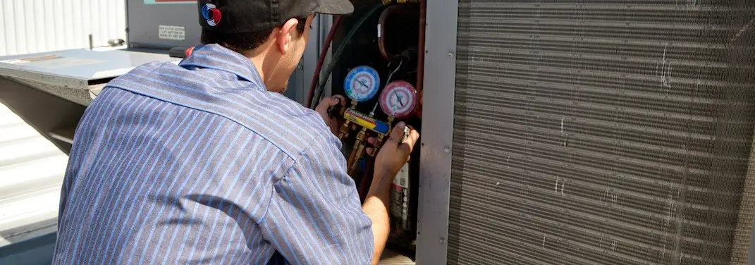 HVAC technician servicing a condenser unit in North Olmsted